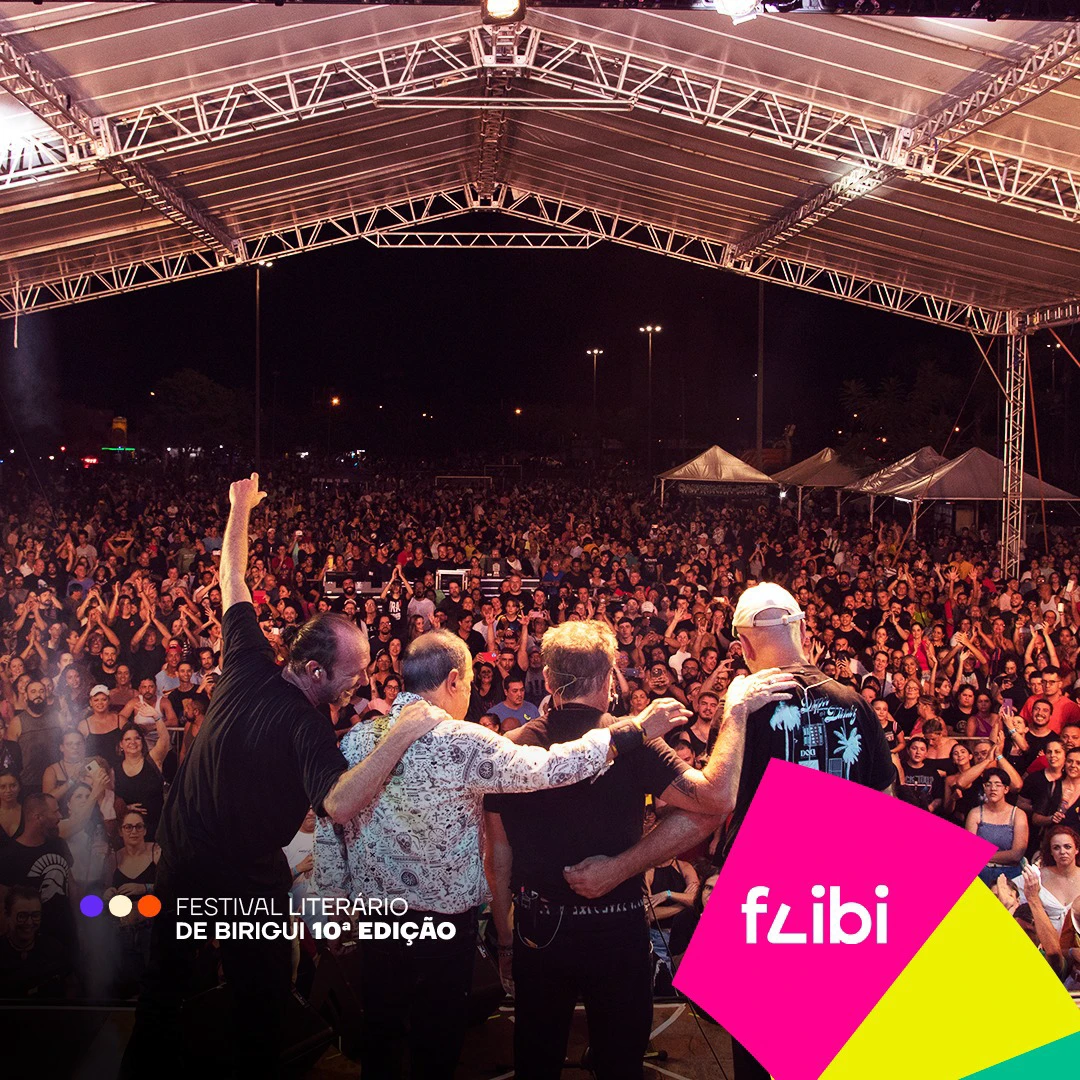 A banda agradece de braços dados no fim do show, de costas para a câmera, diante da multidão que lota o parque.