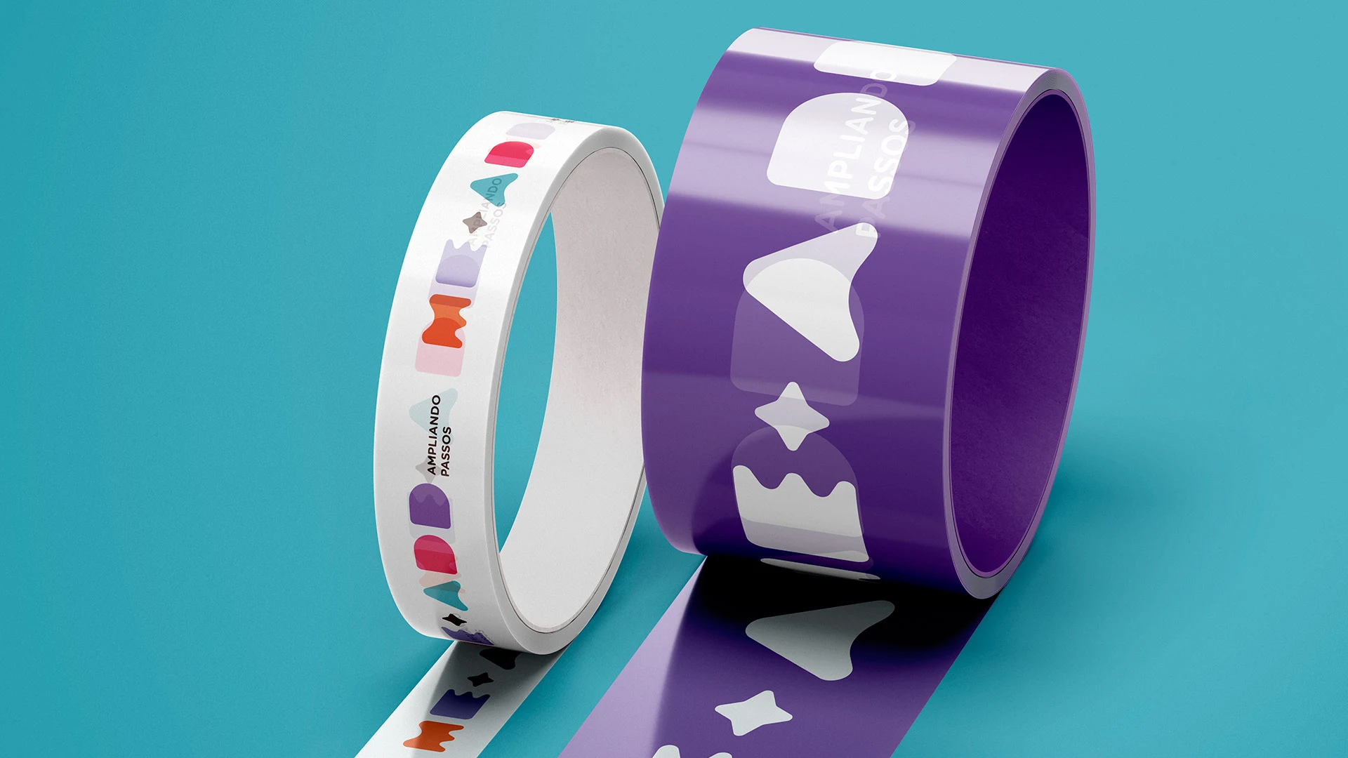 Dois rolos de fita adesiva da Meadd sobre fundo turquesa: o branco com as formas coloridas da marca e o roxo com as formas em branco, ambos com o mote “Ampliando passos”.